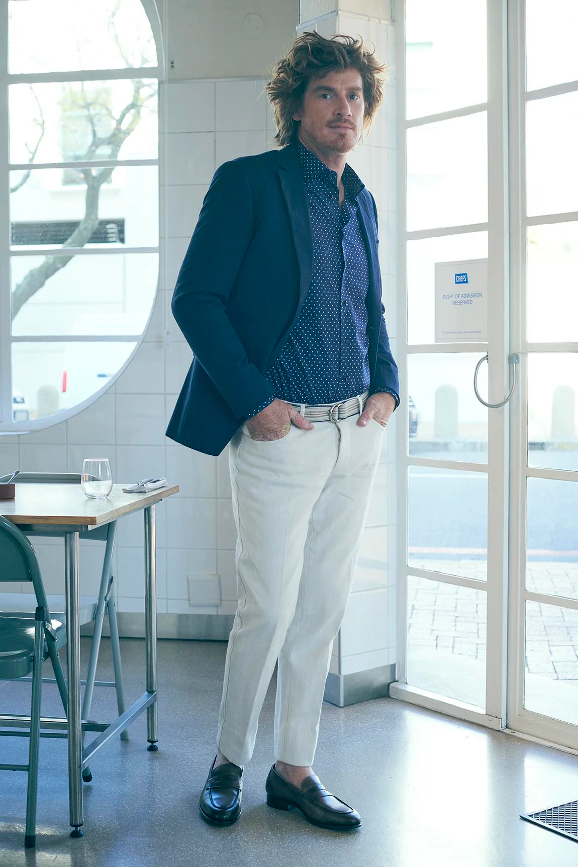 Ein Mann steht an einem Fenster in Denim gekleidet